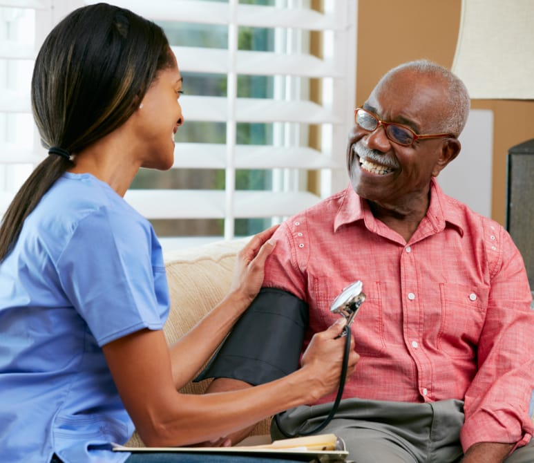 nurse aide taking elderly man's blood pressure
